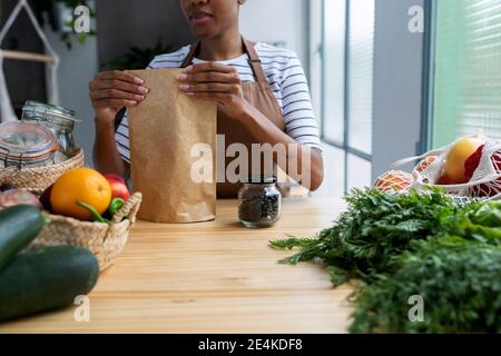 Woman with apron in kitchen , unpacking freshly bought organic fruit and vegetables Stock Photo