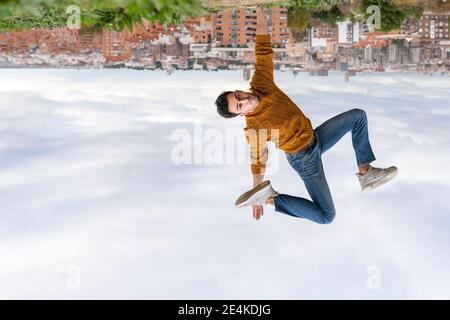 Upside down image of young man doing handstand against city Stock Photo