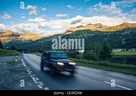 Off-Road car driving along asphalt road in Engadin valley Stock Photo