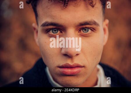 Young man with blue eyes in autumn forest Stock Photo