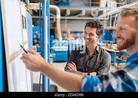 Two carpenters talking over documents in production hall Stock Photo