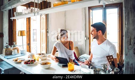Happy young couple with tablet having breakfast at home Stock Photo
