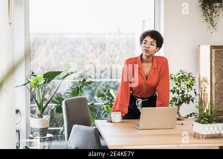 Woman standing at table with laptop at home Stock Photo