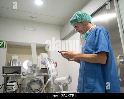 Male orthopedic surgeon performing operation on patient knee in ICU Stock Photo