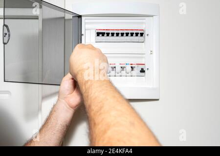 Electrician installing panel with electric meter in apartment of customer Stock Photo