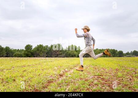 Young man jumping and posing mid-air in grassy field Stock Photo