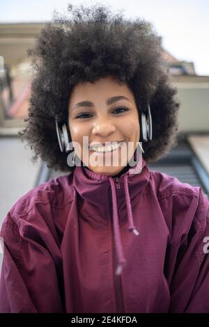 Afro young woman contemplating while listening music while standing against built structure Stock Photo