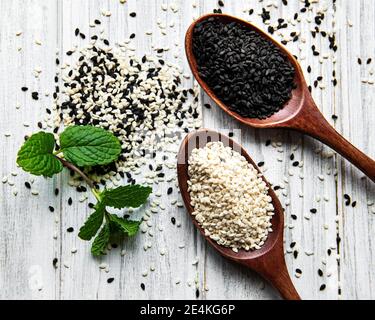 Healthy food and drink concept. Black and white sesame seeds in a spoons on a wooden table Stock Photo