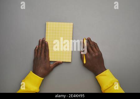 Minimal grey background of African-American male hands holding notebook or diary at desk, top down view, copy space Stock Photo