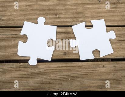 White puzzle piece on a walnut wooden table Stock Photo