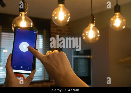 Smart home. Hand controlling smart lamps with app on the phone. Electric concept. Stock Photo