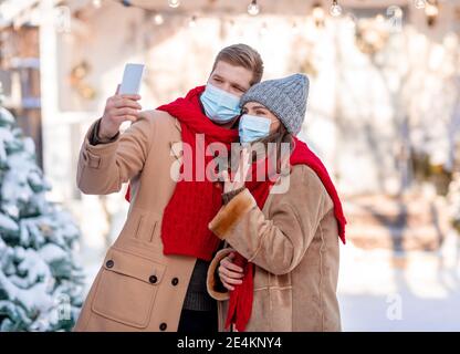 Young couple spending winter holidays together, taking selfie outdoors Stock Photo