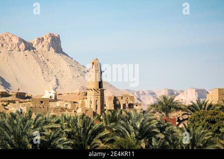 Abandoned old village el-Qasr in the oasis Dakhla, palms in the front, Egypt Stock Photo