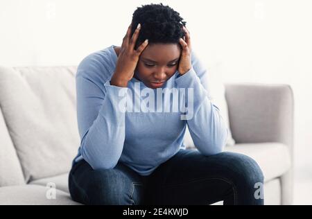Tired black woman touching her head feeling stress Stock Photo