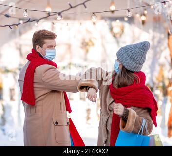 Man and woman in protective masks greeting on street Stock Photo