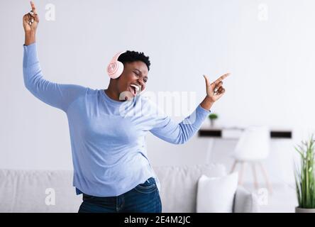 Black woman listening to music in headphones and dancing Stock Photo