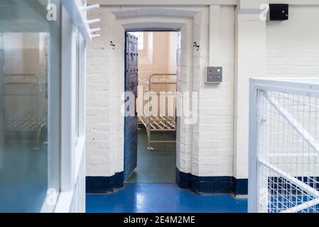 Looking into prison cell block landing victorian British English jail house bed in room lock up high security room derelict old new category A B C Stock Photo
