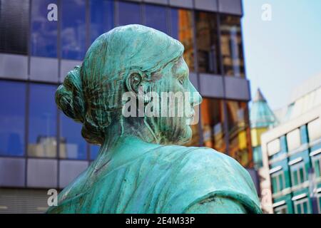 Old bronze sculpture of a woman, allegoric part of the Bismarck monument in downtown Düsseldorf, unveiled in 1899. Modern buildings in the background. Stock Photo