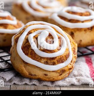 Closeup of baked cinnamon rolls with white icing on a cooling rack Stock Photo