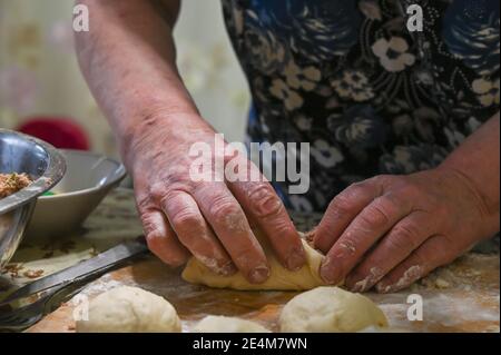 Baker makes  small meat pied. Raw dough balls on wooden board. Stock Photo