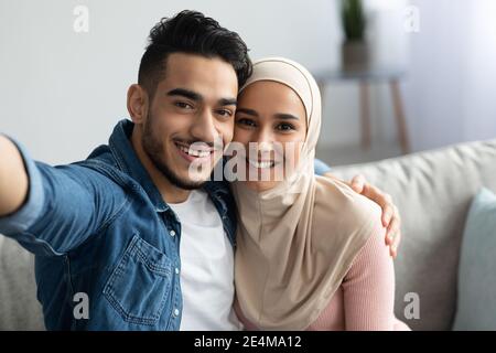 Beautiful muslim man and woman in hijab taking selfie Stock Photo