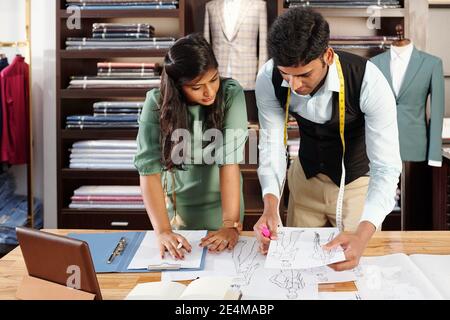 Indian team of tailors checking fashion drawings when preparing new collection Stock Photo