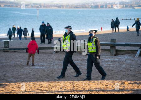 Portobello, Scotland, UK. 24 January 2021. Large numbers of members of the public at Portobello beach and promenade on sunny Sunday afternoon during lockdown. While most people observed social distancing groups of people formed at some of the cafes offering takeaway food and drinks. Police patrols spoke to public sitting down and in groups at cafes to ask them to move on. Iain Masterton/Alamy Live News Stock Photo