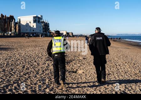 Portobello, Scotland, UK. 24 January 2021. Large numbers of members of the public at Portobello beach and promenade on sunny Sunday afternoon during lockdown. While most people observed social distancing groups of people formed at some of the cafes offering takeaway food and drinks. Police patrols spoke to public sitting down and in groups at cafes to ask them to move on. Iain Masterton/Alamy Live News Stock Photo