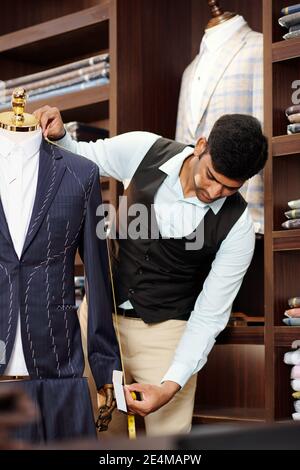Professional tailor measuring sleeve length of bespoke jacket he is making Stock Photo
