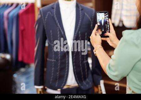 Female atelier manager phototgraphing almost ready bespoke jacket on mannequin Stock Photo