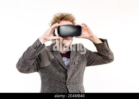 Young curly-haired businessman wearing brown suit use a VR headset and experiencing virtual reality isolated on white background Stock Photo