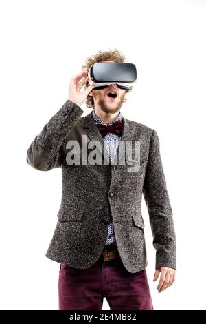 Young curly-haired businessman wearing brown suit use a VR headset and experiencing virtual reality isolated on white background Stock Photo