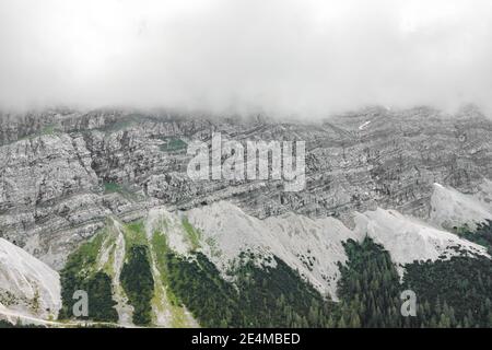 Aerial drone shot of rock cliff of Zugspitze covered with heavy fog in Germany Stock Photo