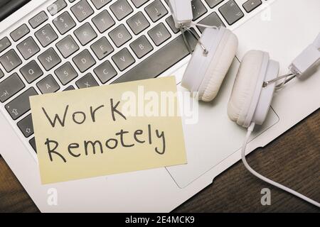 Work remotely. Memo stick on laptop keyboard with headset and pen.  Modern technologies in business. Stock Photo