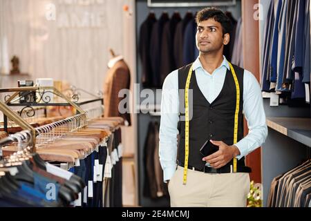 Young Indian sales manager with measuring tape working in man clothes store Stock Photo
