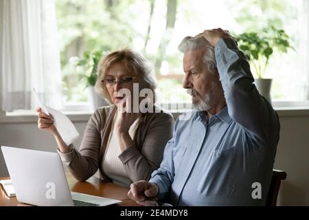 Unhappy mature man and woman reading documents, problem with money Stock Photo