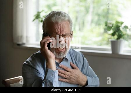 Close up unhappy mature man touching chest, calling emergency Stock Photo