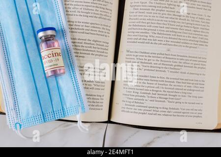 22 JANUARY 21 New York US 2021: Opened the Holy Bible close up prayer time with Negative attitude of the church to vaccination and covid-19 vaccine bottle Stock Photo