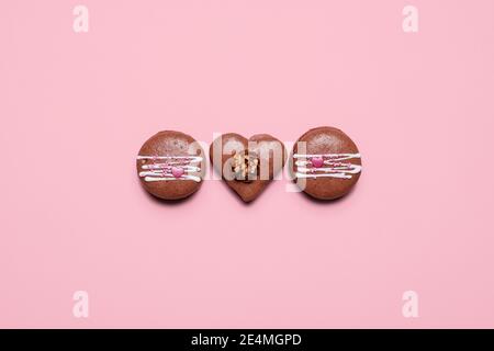 Three Valentines Day macarons with Love written in icing on a pastel pink background.  Three chocolate with copy space and room for text Stock Photo