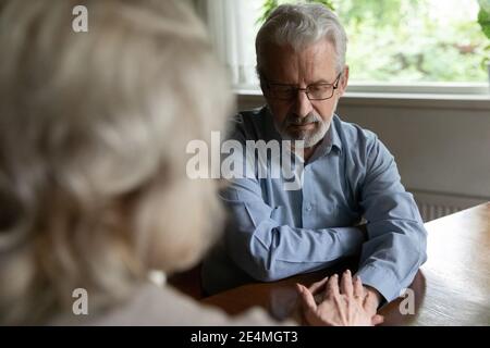 Rear view caring mature wife comforting frustrated husband, holding hands Stock Photo