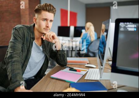 Thoughtful male IT specialist sits at the table Stock Photo