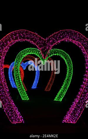Heart shaped arches love tunnel glowing with colorful garland lights Stock Photo