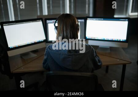 Female hacker in headphones works on computer Stock Photo