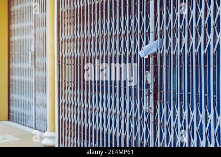 White paper notification attached to closed retractable folding metallic  gate.Metal collapsible sliding grille door normally use at shop houses in  Asi Stock Photo - Alamy
