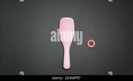 Odessa, Ukraine - December, 14 2020: A trendy light pink color hair care kit of Tangle Teezer hairbrush with Invisibobble hair ring on dark gray Stock Photo