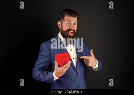 Celebrate love. Trust me. Happy valentines day. Tuxedo man hold red heart. Love concept. Passionate mature lover hipster in formal suit. Businessman with bow tie. Romantic greeting. Fall in love. Stock Photo