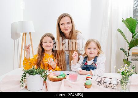 Mother and her two daughters posing for a photo, they all painting easter eggs Stock Photo