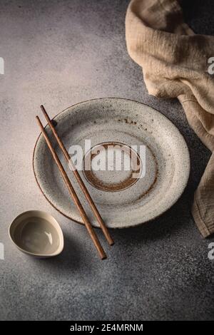 Empty plate with sushi chopsticks and gravy boat on gray table Stock Photo