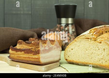 Bread with smoked bacon on a wooden background with space for text. Smoked balyk and bacon on sacking. Salted fat in spices on a wooden board Stock Photo