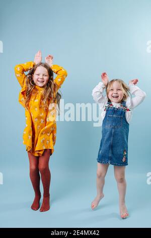 Funny little sisters making easter bunny ears gesture with hands Stock Photo